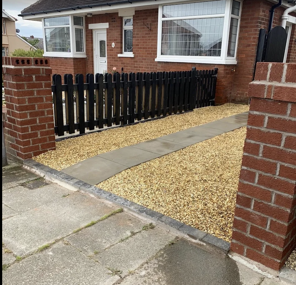New gravel driveway with concrete path and brick pillars